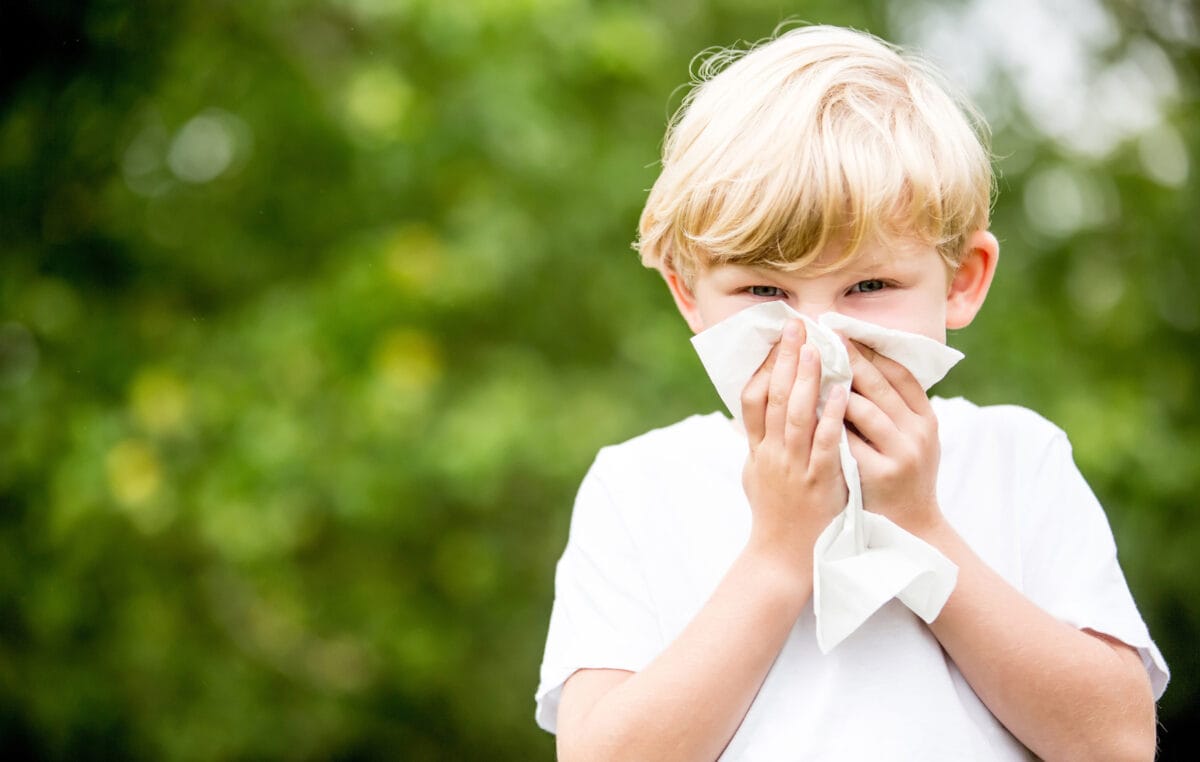 Child outside holding a tissue over their nose. Eczema and Allergy in Kids - Integrative Health