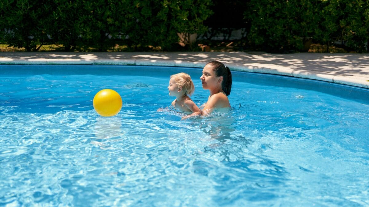 Mom and toddler playing with a ball inside a pool