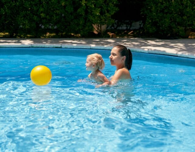 Mom and toddler playing with a ball inside a pool