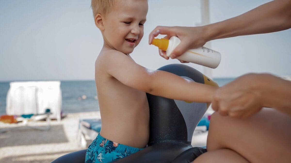 Mom applying sunscreen to toddler at the beach